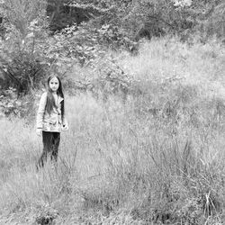 Portrait of woman standing on grassy field