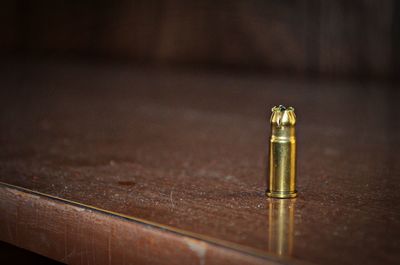 Close-up of gold bullet casing on table