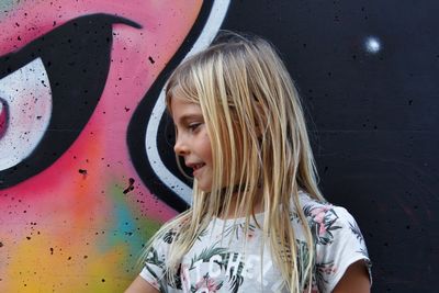 Smiling girl looking away against painted wall