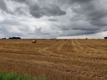 Hay bales on field against sky