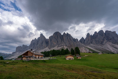 Houses on field by mountains against sky