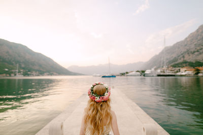 Rear view of woman looking at lake against mountains