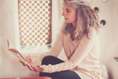 Mature woman reading book at home