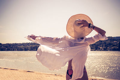 Rear view of carefree woman with straw hat enjoying in summer breeze at the beach. copy space.