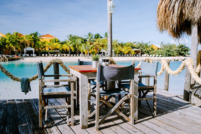 Chairs and tables at swimming pool against sky