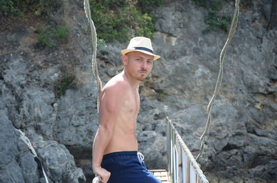 Full length of shirtless man standing on rock