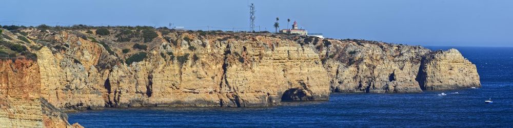 Rock formations by sea against blue sky