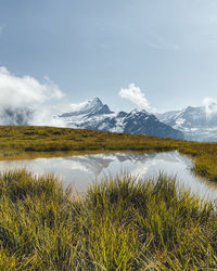 Scenic view of pond by mountains against sky