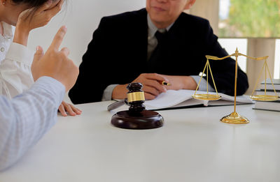 Midsection of lawyer sitting with couple at office