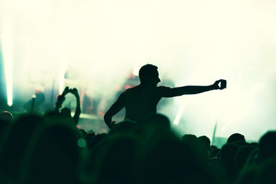 Silhouette of hands on a concert in front of bright stage lights