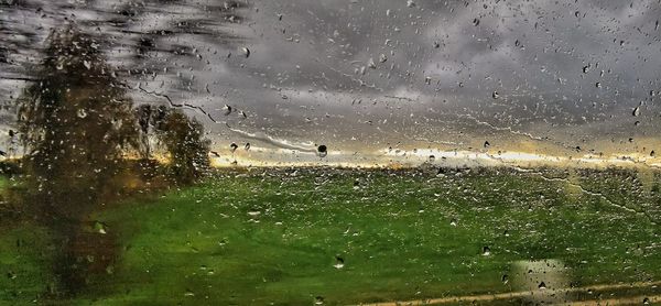 Water drops on glass window against sky during rainy season