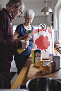 Retired senior couple with groceries on kitchen counter at home