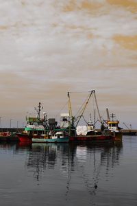 Fishing boats at harbor against sky