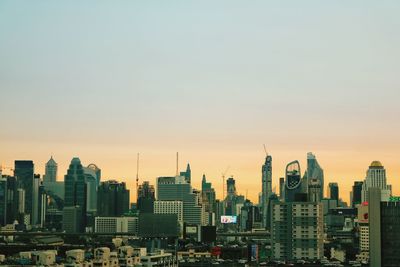 Modern buildings in city against sky during sunset