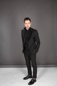 Portrait of young man standing against wall