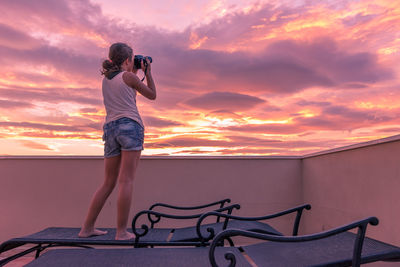 Man photographing against sky during sunset