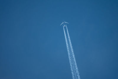 Low angle view of airplane flying against blue sky