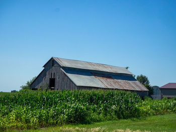 House on field against clear blue sky