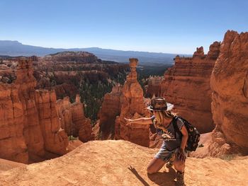 Woman gesturing towards rock formation at bryce canyon