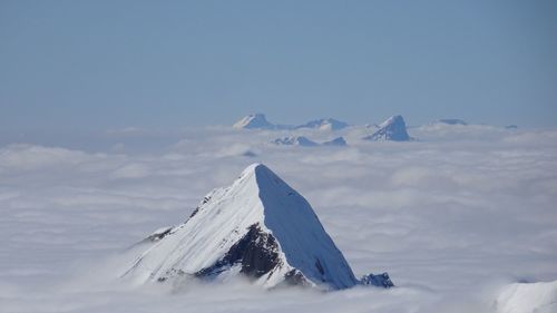 Scenic view of snowcapped mountains against cloudy sky