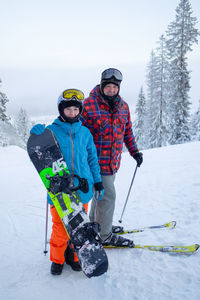 Family - daughter snowboarding and father skiing down the ski slope