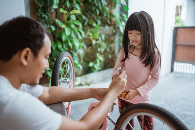 Father repairing bicycle with daughter at home