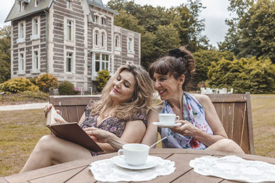 Friends using mobile phone while sitting on table