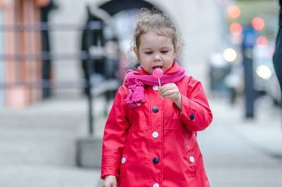 Girl in pink jacket holding lollipop