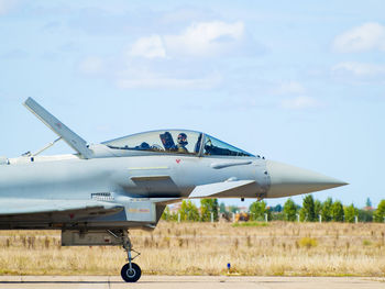 Side view of airplane flying over field against sky