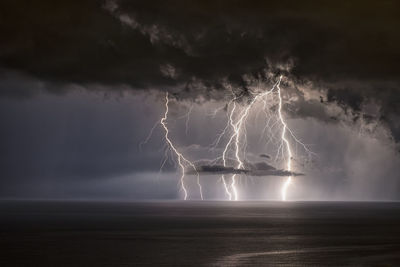 Lightning over sea against storm clouds