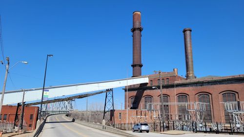 Cars on road by buildings against clear blue sky