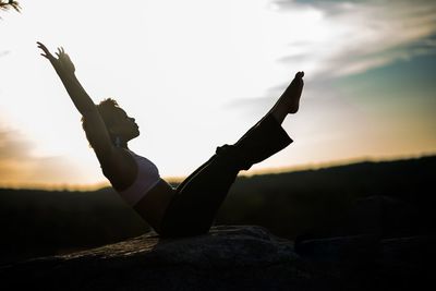 Low angle view of silhouette person on rock against sky during sunset