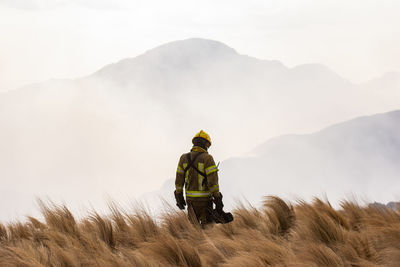 Rear view of man on field against mountain range