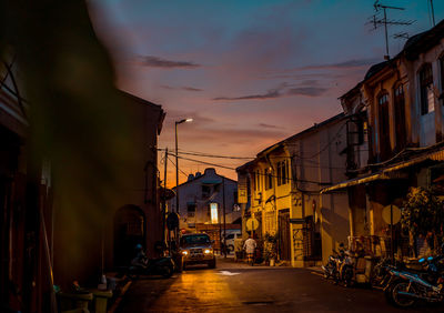 Street amidst buildings against sky during sunset