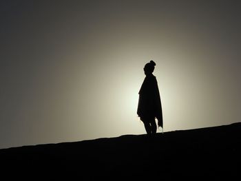 Silhouette woman standing on land against clear sky during sunset