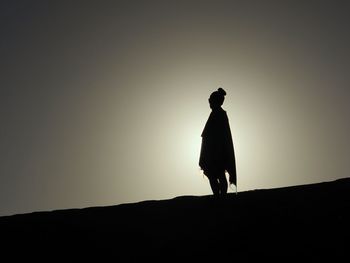 Silhouette man standing on mountain against clear sky during sunset