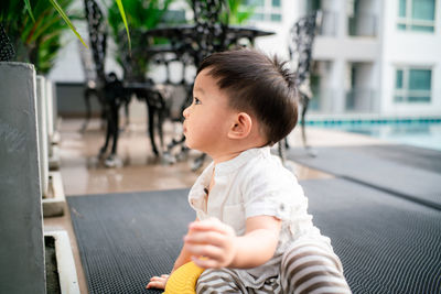 Cute boy looking away while sitting outdoors