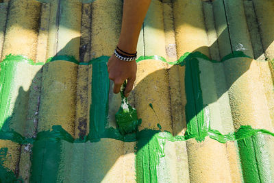 Cropped hand of person painting on rooftop