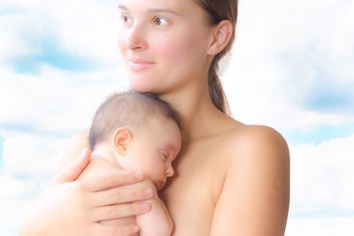 Happy mother with daughter standing against sky