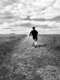 Rear view of teenage boy running on land