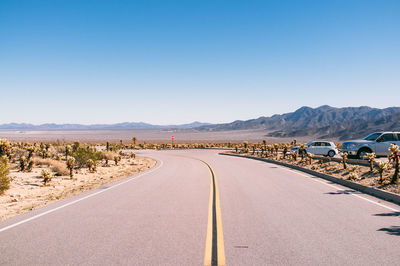 Road by mountains against clear sky