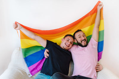 Two homosexual men holding lgbtq flag.