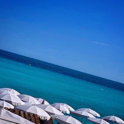 Scenic view of swimming pool by sea against clear blue sky