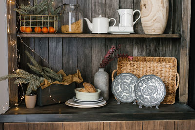 Kitchen utensils are on the shelves in a wooden cabinet, fir branches as decor for christmas