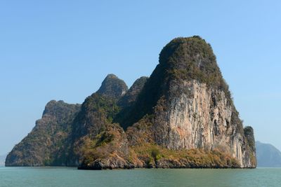 Rock formations by sea against clear blue sky