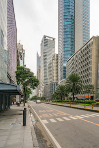 City street by modern buildings against sky