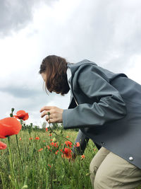 Rear view of person on poppy field against sky