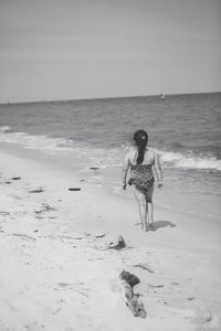Full length of girl walking at beach against sky
