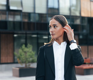 Young businesswoman standing against building