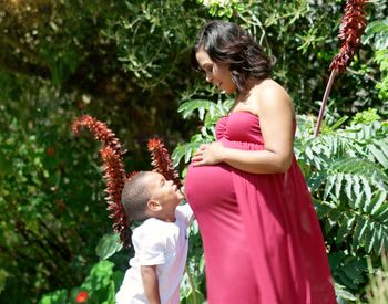 Pregnant woman and son standing against plants 